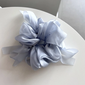 Macro detail of a light blue organza ribbon scrunchie with soft fabric texture