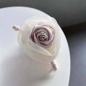 Détail d'une pince à cheveux rose en satin et organza avec des motifs floraux