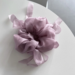 Detail of light purple organza scrunchie with long ribbons on a white surface