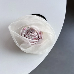 Vue détaillée d'un chouchou floral avec organza blanc et pétales en tissu fleuri rose