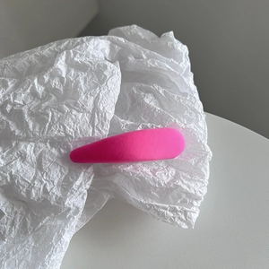Détail d'une pince à cheveux macaron rose vif avec texture tissée sur papier blanc