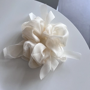 Detail of cream organza hair scrunchie with soft sheen and layered pleated ribbon design