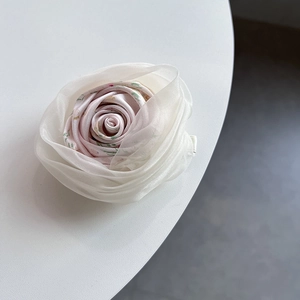 Gros plan d'une pince à cheveux fleurie en tissu avec pétales multicouches élégants