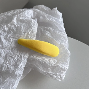 Détail d'une pince à cheveux goutte en tissu jaune avec une texture côtelée fine