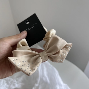 Elegant beige satin scrunchie with sparkling rhinestones shown against a lace background