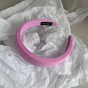 Detail of pink fabric headband with handmade label on white textured background