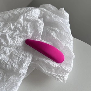 Gros plan d'une pince à cheveux ovale en tissu magenta sur un papier d'art blanc texturé
