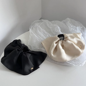 Detail view of premium satin fabric hair claws in black and cream with pleated texture