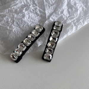 Detail shot of K9 crystal rhinestones on black hair clips against a white background