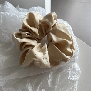 Macro shot of elegant champagne silk hair scrunchie with sparkling rhinestone details