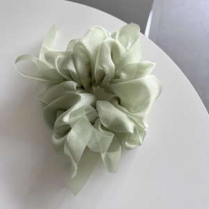 Detailed texture of light green organza scrunchie with long ribbons and silky finish