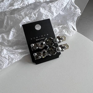 Detail view of flower hair clips with grey pearls and faceted crystals on display card