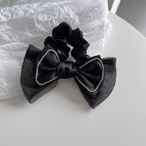 Détail d'un chouchou nœud noir avec tissu organza multicouche et bordure de strass