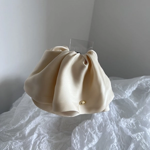 Close-up of champagne silk scrunchie with elegant pleats and a gold oval metal buckle