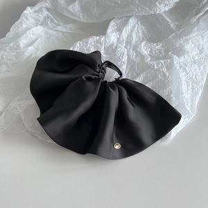 Detail view of black silk satin ruffled hair claw with elegant gold hardware accents
