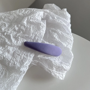 Gros plan détaillé d'une pince à cheveux en tissu violet sur un support en papier blanc