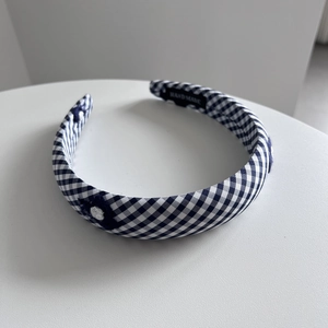 Détail du serre-tête vichy bleu avec broderie florale et étiquette faite à la main