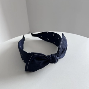 Vue détaillée d'un serre-tête bleu marine avec nœud et motifs à pois blancs