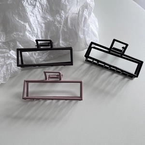 Three matte rectangular hair claws in black, burgundy and rose pink on white surface