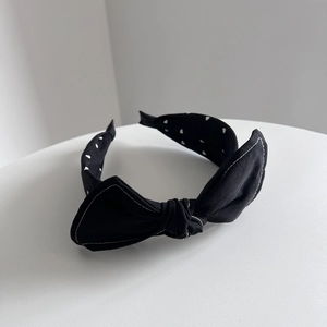 Détail du serre-tête en tissu noir à motifs de cœurs et surpiqûres contrastées