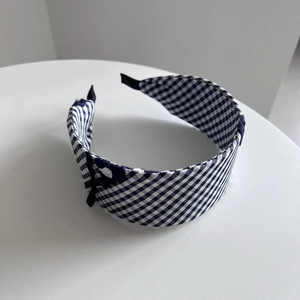 Détail du serre-tête large à carreaux bleus avec nœud en ruban noir et broderie de fleurs