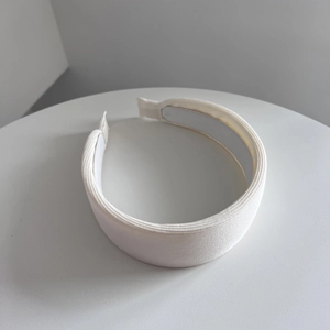 Dettaglio del cerchietto in maglia color crema con trama a coste e fodera antiscivolo