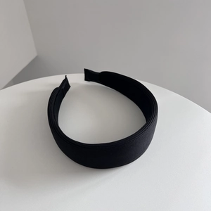 Cerchietto largo in tessuto nero minimalista con trama fine su sfondo bianco