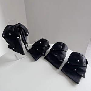 Close-up of black satin bow hair clips with faux pearls and layered 3D ribbon texture