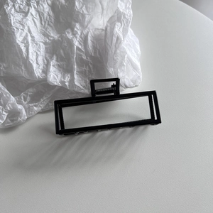 Detail of a large matte black rectangular hollow hair claw clip with a strong metal spring