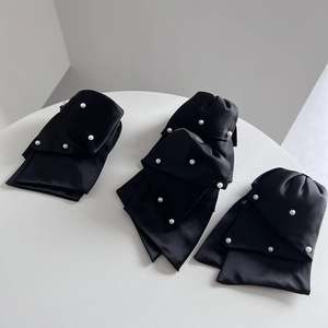 Close-up of elegant black satin hair clip with white pearls and silk texture finish
