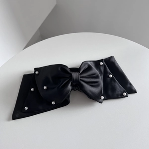 Macro detail of elegant black satin bow hair claw clip with delicate white pearls