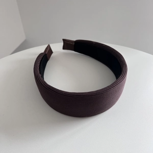Dettaglio ravvicinato del cerchietto in maglia marrone scuro con trama verticale vintage