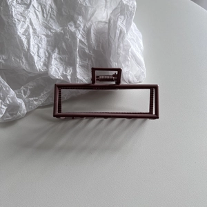 Macro shot of rectangular dark brownish-red matte hair claw with metal spring mechanism