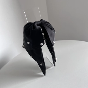 Detail of elegant black satin bow hair claw with white pearls on a minimalist display
