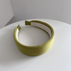 Dettaglio della trama del tessuto a coste verde erba su questa ampia fascia per capelli