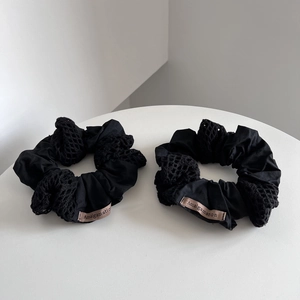 Detail of black cotton scrunchies with hollow mesh crochet and woven label