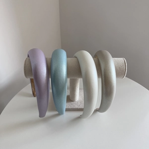 Set of four padded sponge headbands in pastel pearlescent colors on a display stand