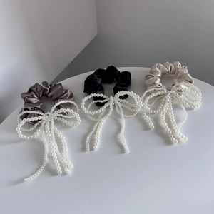 Detail van satijnen scrunchies in bruin zwart en champagne met parelstrik en kwastjes