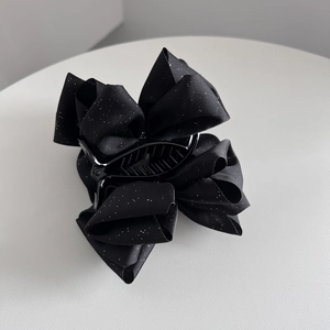 Détail macro de la pince à cheveux noeud noir élégante avec finition pailletée sur tissu