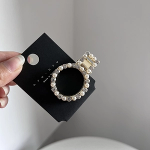 Detailed macro view of a gold-toned circular hair clip with inlaid pearls and rhinestones