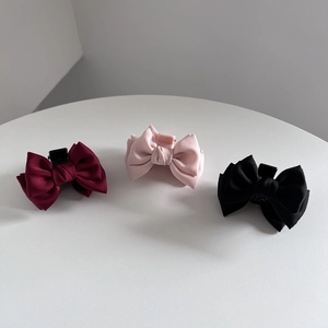 Detailed view of matte satin bow hair clips in burgundy, pink, and black colors