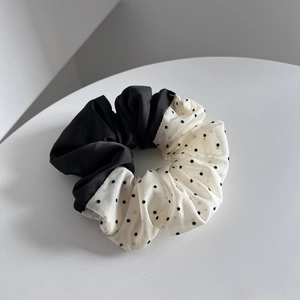Detail of a two-tone scrunchie featuring black satin and white polka dot fabric
