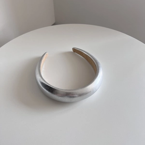 Detail of silver sponge headband with metallic leather texture and beige fabric lining
