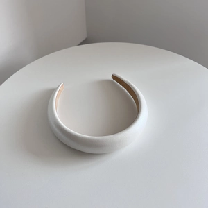 Close-up of white padded sponge headband with subtle leather texture and tan non-slip lining