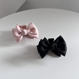 Detailed view of pink and black silk bow hair clips with a sturdy plastic claw design