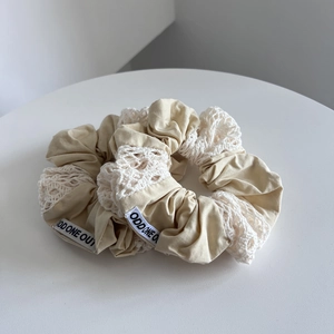 Detail of cotton lace scrunchies with intricate hollow embroidery and brand label