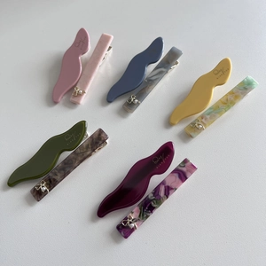 Detail view of acetic acid hair clips set with marbled patterns and pearl bow accents