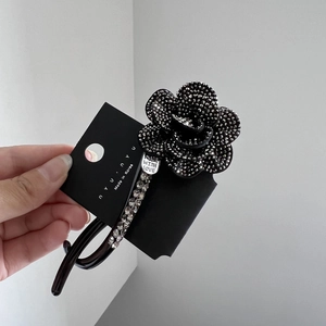 Detail view of camellia hair clip with rhinestones and Made With Love silver tag