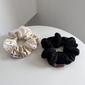 Detail of two-tone cotton scrunchies with intricate lace splicing and brand woven labels