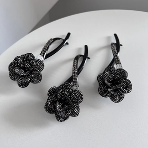 Detailed view of black camellia hair clips with rhinestones and silver tag with love